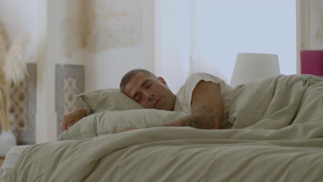 handsome man sleeping in bed in morning on weekend