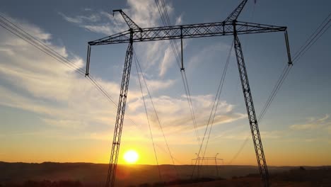 dark silhouette of high voltage tower with electric power lines at sunrise. transmission of electric energy concept