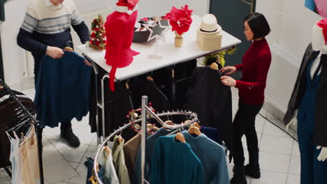 busy clothing shop filled with customers in christmas frenzy looking to buy perfect gifts for friends and family. clients in shopping spree at mall boutique during winter holiday season