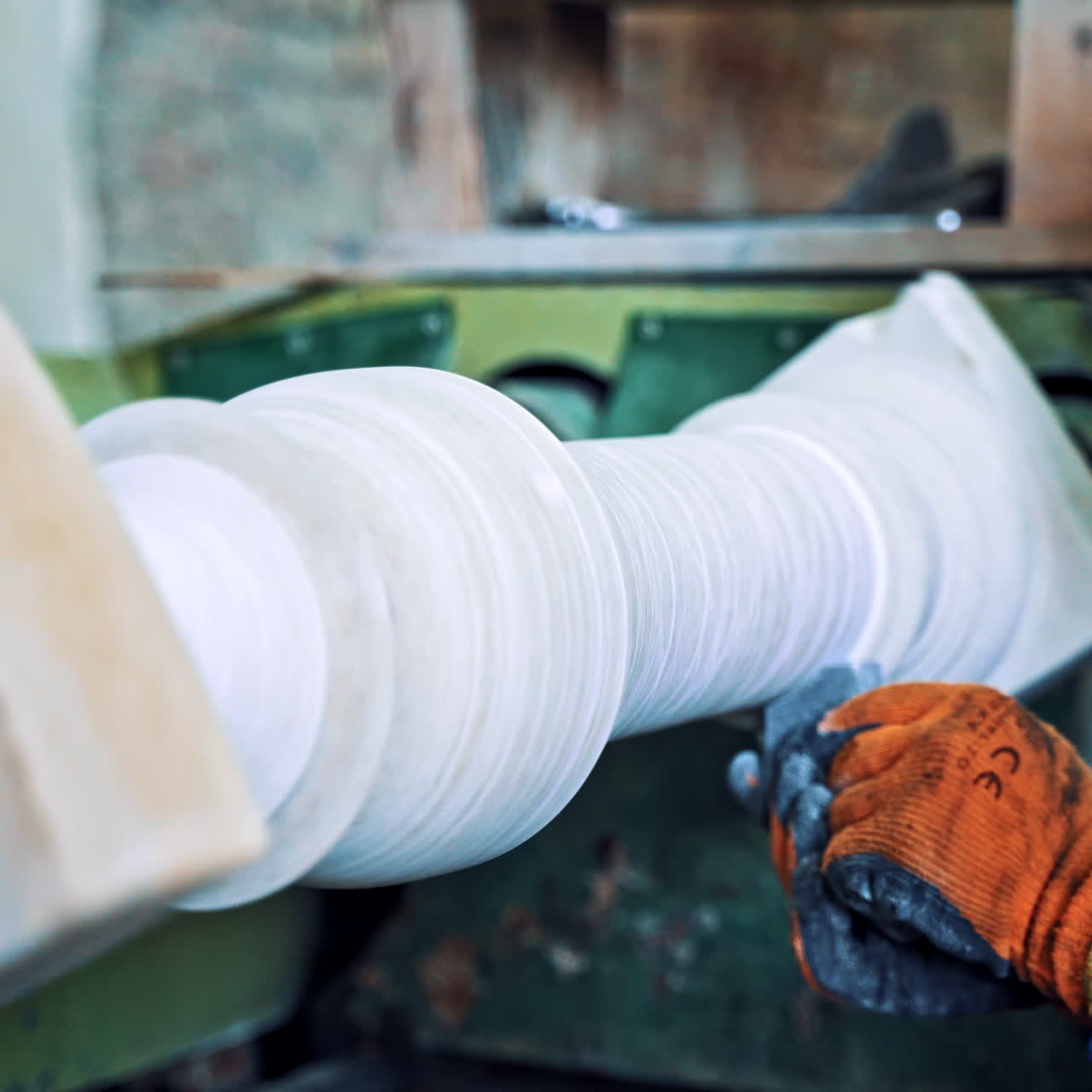 Worker man in special uniform with mask polishing stone in workshop. Laborer is working at the grinder machine on the old factory background. Camera moves forward.