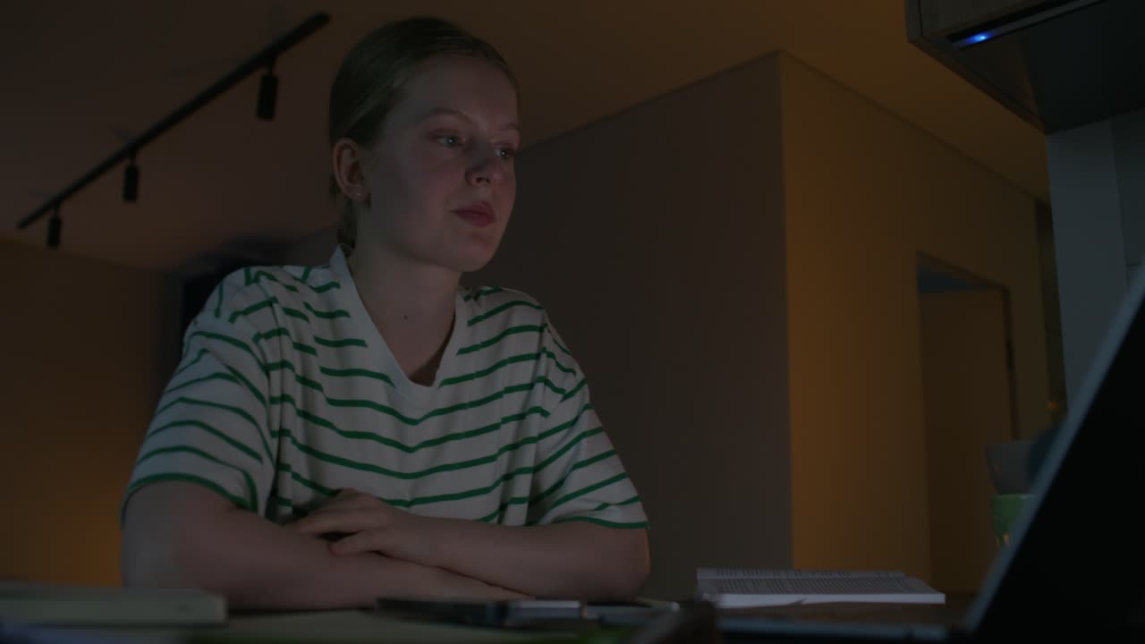 una adolescente estudiando hasta tarde en la noche en casa