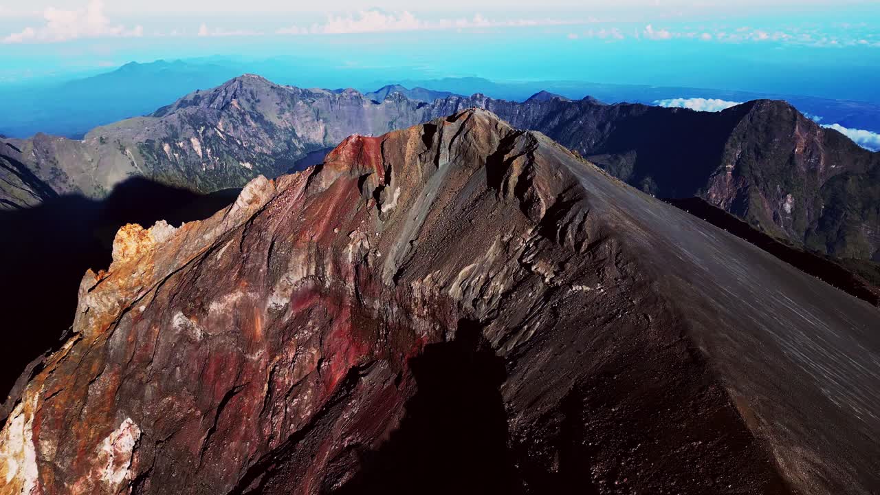 Stunning aerial footage of climbers enjoying the summit of Mount Rinjani volcano with crystal clear views of the crater lake and mountainous terrain.