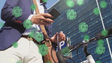 animation of covid-19 cells over asian man wearing face mask with bicycle using smartphone outdoors