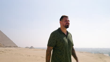 un hombre en el desierto en primer plano con la meseta de giza en el fondo en giza, egipto.