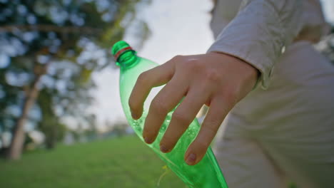 volunteer hand holding plastic bottle at cleanup eco-action in park closeup.