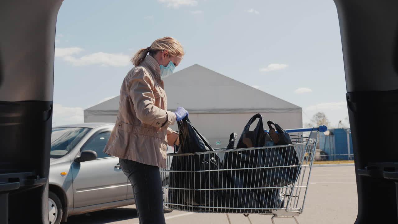 Acquirente mette gli acquisti nel bagagliaio dell'auto durante la quarantena