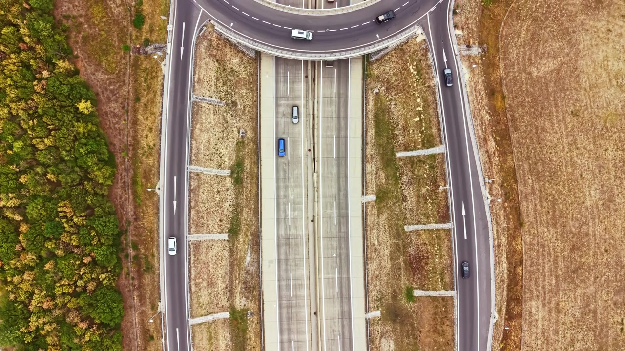 Highway scene showing multiple lanes with vehicles moving under a clear sky near fields and trees during the day