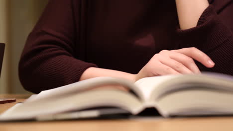 tracking shot of a woman's hand changing the page of the book she is reading, flipping a page