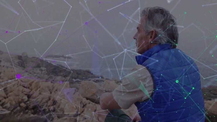 Senior man sitting on rocky shoreline gazing toward ocean, featuring glowing tech network overlay