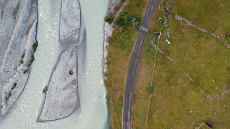 Road-passing-through-countryside-near-a-river-in-Norway-aerial-drone-shot