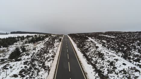 Lange-Straßenantenne,-Die-Die-Entfernung-über-Verschneite-Landschaftsmoore-Im-Hochland-Aufzeigt