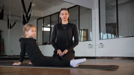young girl stretching with instructor in fitness studio