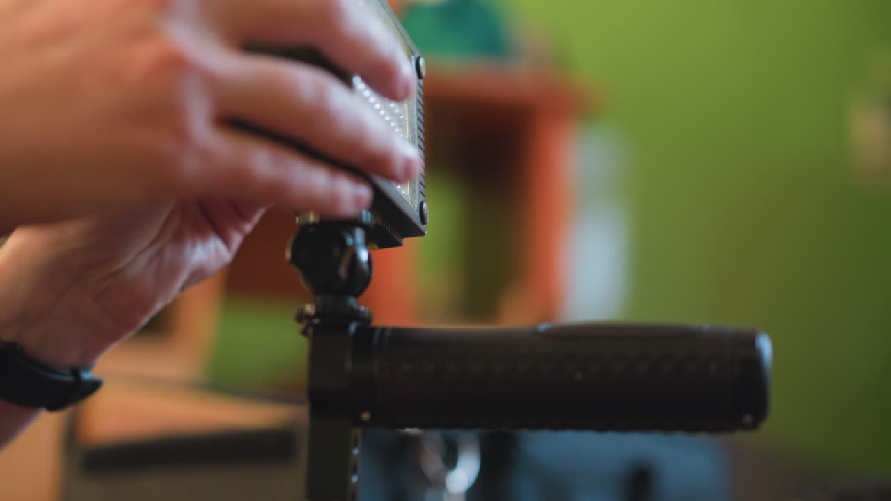 close-up of hands adjusting camera rig on tripod, setting up gear for filming. preparing equipment, microphone, and camera for video production shoot. professional video production setup