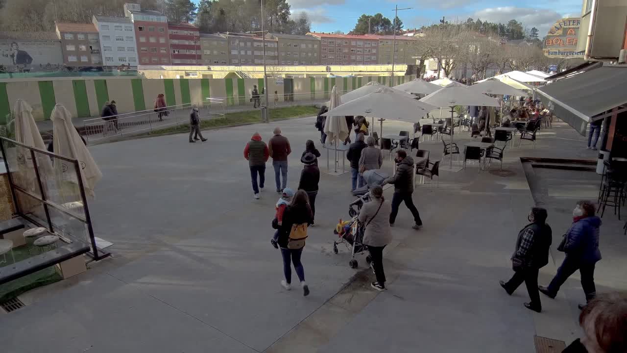 Group Of Locals Coming Down Stairs Onto Street In Ordes In Spain. Pan Right
