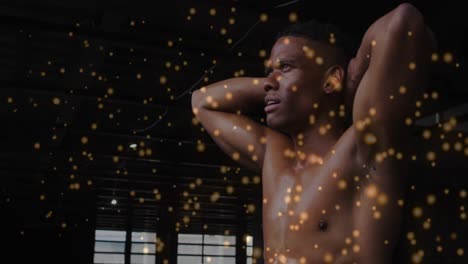 Animation-of-floating-golden-dots-over-man-flexing-his-muscles