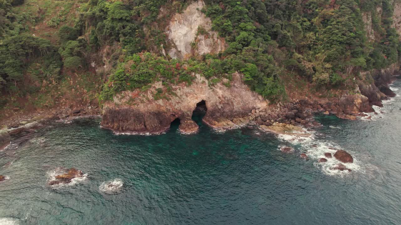 Aerial cave entering cliff in Japanese Kyotango Blue Sea landscape, drone slow natural environment of rocks and green cliff, Japan Kansai, travel destination