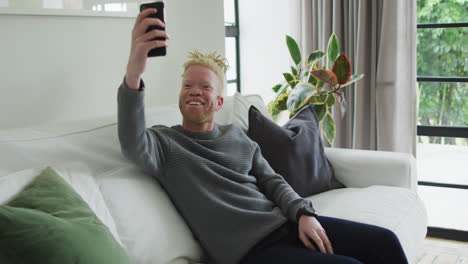 happy albino african american man with dreadlocks using smartphone