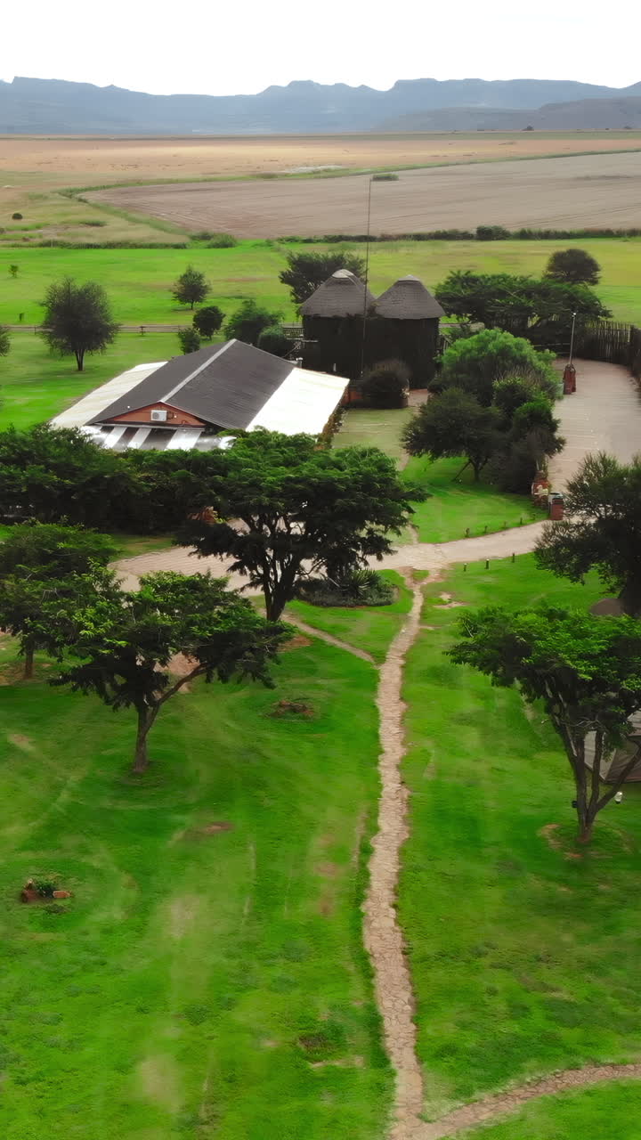 Vista aérea de un lodge rural con edificios de techos de paja y campos verdes