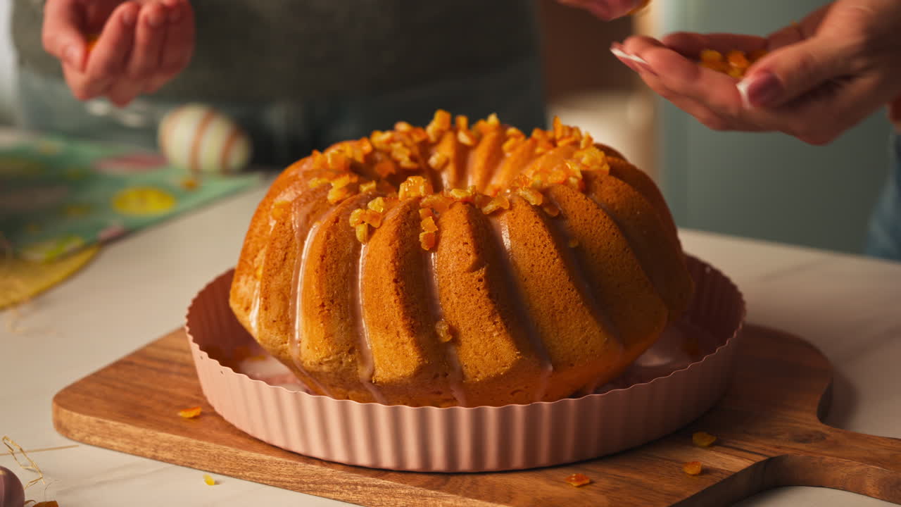 Tart Kalıbındaki Sırlı Paskalya Bundt Keki Üzerine Şekerlenmiş Portakal Parçacıkları Serpen El. Yakın çekim.