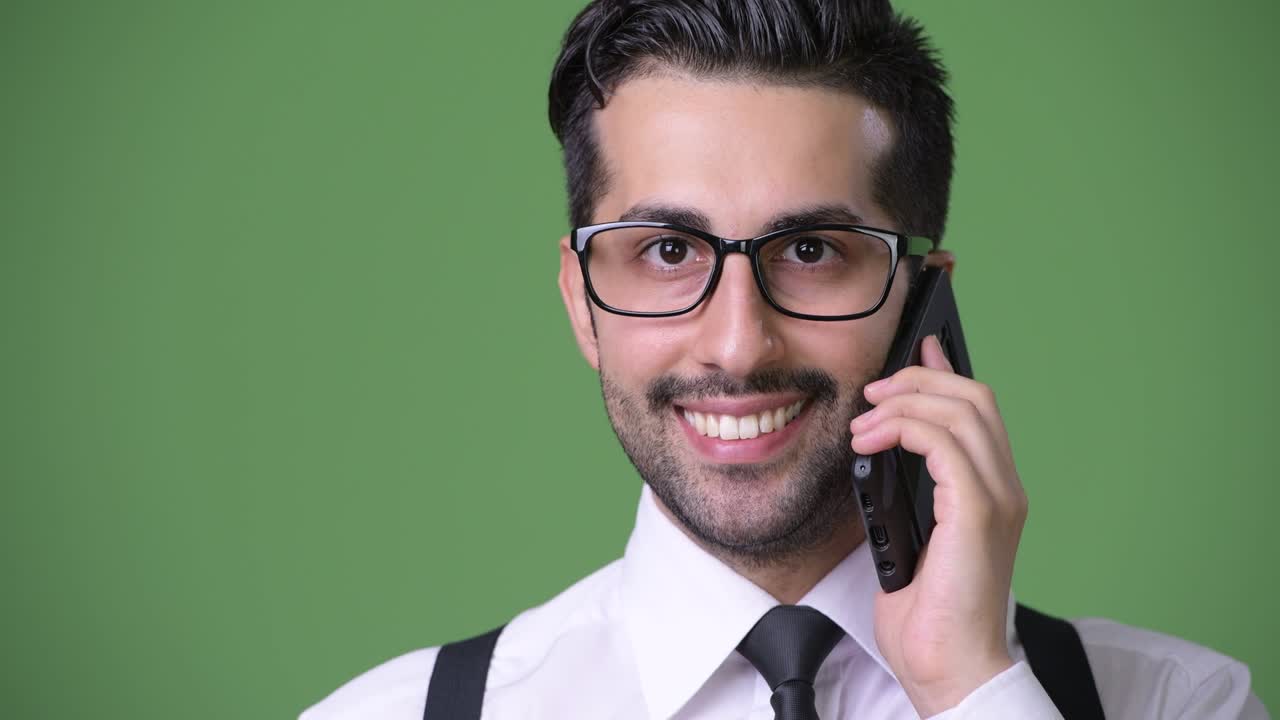 joven empresario persa barbudo y guapo contra un fondo verde