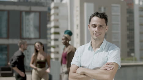 front view of businessman standing on rooftop with folded arms