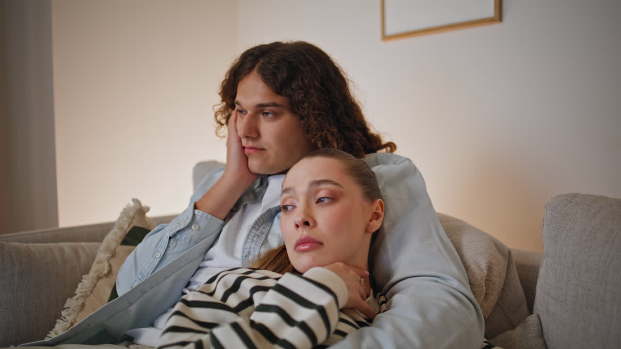 Casal em casa aproveitando um filme, sentado confortavelmente no sofá da sala de estar. Close-up do lar
