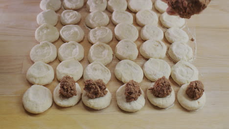 the baker puts the minced meat filling into the dough pieces. cooking dumplings