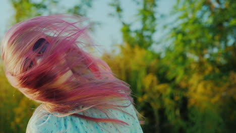 carefree girl in sunglasses with pink hair waving her head