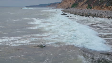 top down birds eye aerial view of the waves crashing on a rocky southern california beach