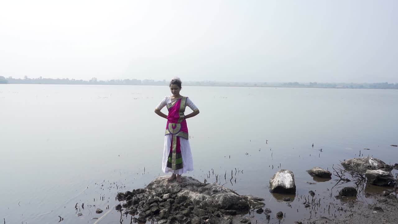 una bailarina de bharatnatyam que muestra una pose clásica de bharatnatyam en la naturaleza del lago vadatalav, pavagadh