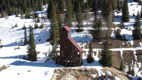 abandoned antique mining structure in colorado mountains with drone shot pulling out