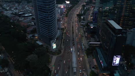 aerial tilting shot following traffic on a multi lane highway into the modern city center with skyscrapers in jakarta