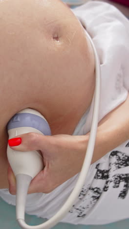ultrasound on pregnant woman's belly. doctor performing sonography to a future mother. close-up. top circling view. vertical video