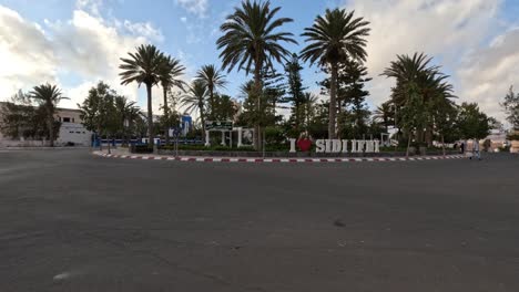 In-the-heart-of-Sidi-Ifni-City,-Morocco,-lies-a-charming-roundabout-adorned-with-graceful-palm-trees