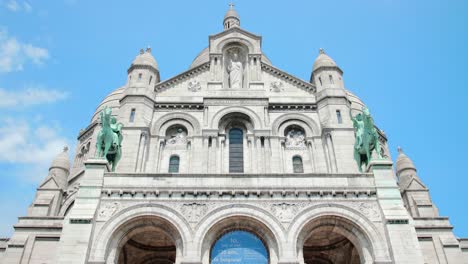 Panning-across-and-looking-up-Sacre-Coeur-Basilica-with-blue-sky-background-in-Paris,-France