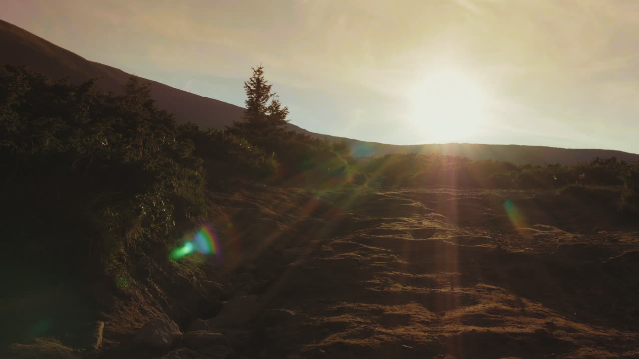 un par de turistas con mochilas y bastones de trekking descienden de la montaña bajo el hermoso sol
