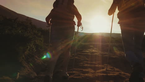 Ein-Paar-Touristen-Mit-Rucksäcken-Und-Trekkingstöcken-Steigen-In-Der-Sonnenschönheit-Den-Berg-Hinab