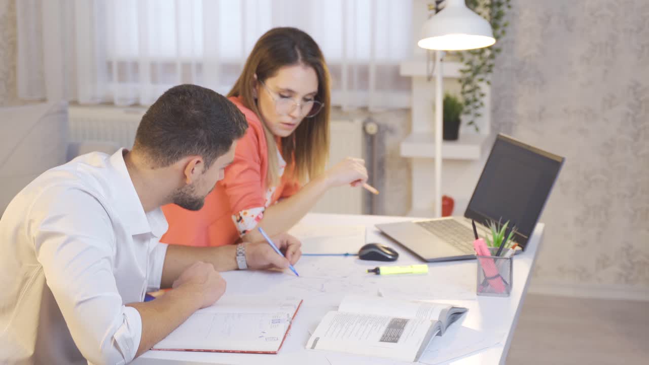los estudiantes universitarios trabajan en casa con computadoras portátiles y mirando libros.