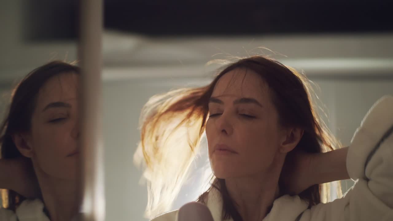 красивая брюнетка сушит волосы феном в ванной комнате дома в замедленной съемке