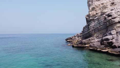 drone shot of rocky cliff on the sea in oman