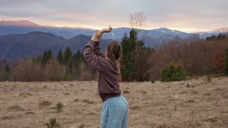 a woman stretching in a field with mountains in the background