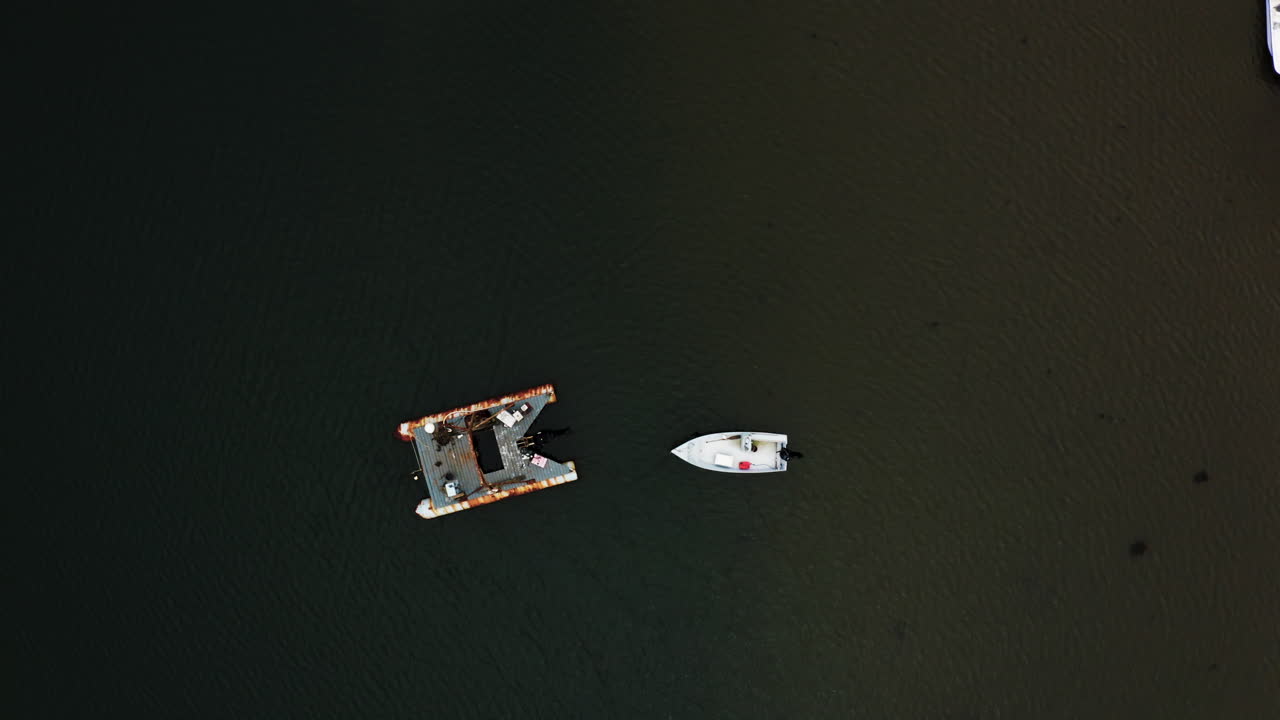 Ripresa aerea dall'alto con drone di una piccola barca e una zattera per la pesca delle aragoste 4k 30p