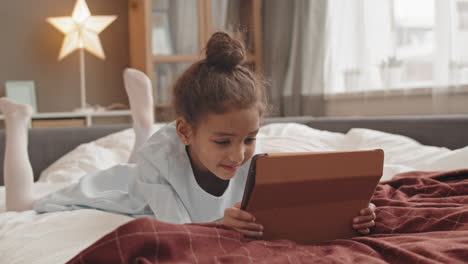 girl using tablet computer in bed