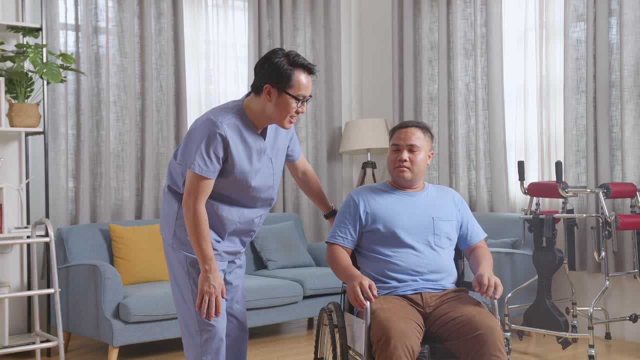 아시아 남성 간호사가 의학적 검사 결과에 대해 이야기하고 집에서 물리 치료 후 체어에서 울고있는 환자를 격려합니다.