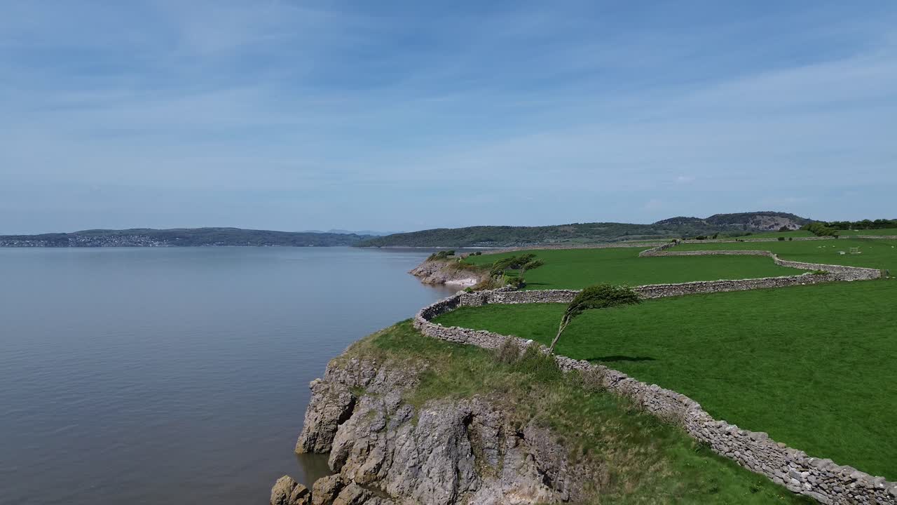Morecambe bay coastal farming meadow aerial view with stone wall boundary and mountain range horizon