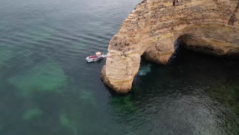 Drone-shot-of-boat-moving-near-Elephant-Rock-on-Portugal-Coast