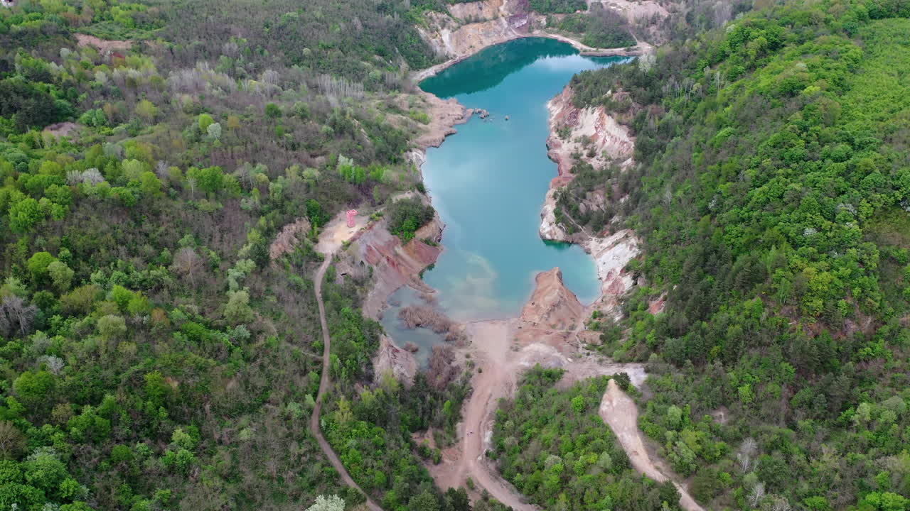 volar hacia abajo sobre la vista de un sitio de construcción de una antigua mina con un lago azul en hungría