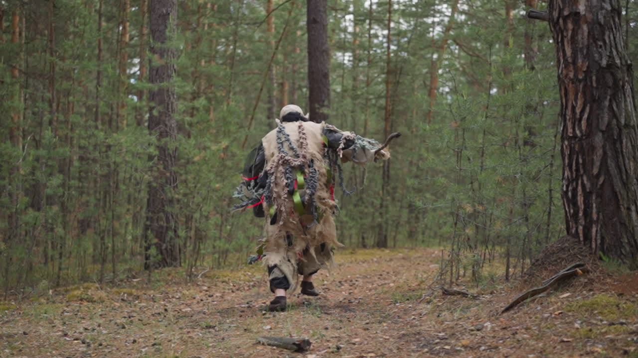 Ogre i snavset tøj med stok løber ad vej i skoven