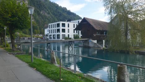 interlaken immersive pov: moving through early morning city streets in switzerland, europe, walking | shaky movement from small path to small mill on turquoise water front