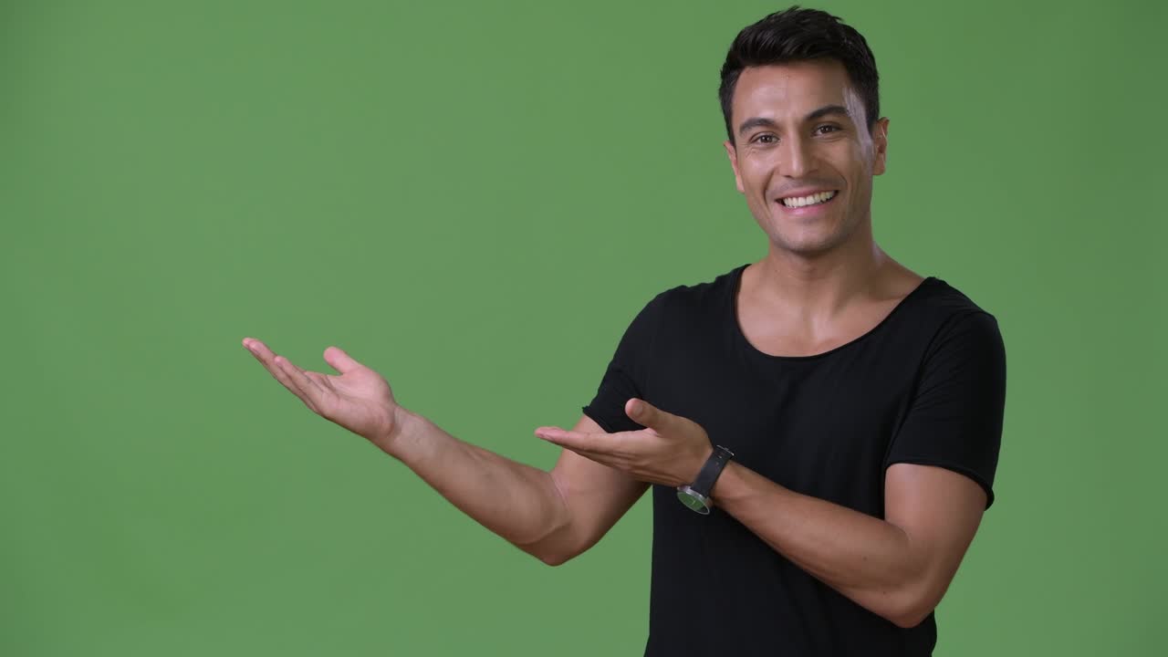 joven y guapo hombre hispano contra un fondo verde